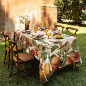 Fruit Love linen tablecloth by The Napking with fruit and foliage on a garden table set with amber glasses.
