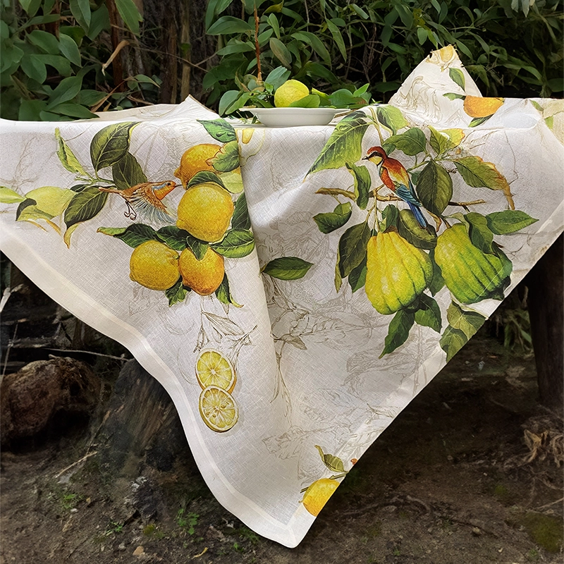 tovaglia limoncello la bottega di casa Tovaglia di lino con limoni Limoncello drappeggiata in giardino, con cedri, foglie verdi e fondo chiaro