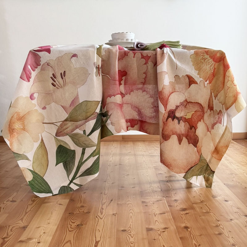 Peony Linen Tablecloth-la-bottega-di-casa Peony linen tablecloth draped over a table, with oversized pink and peach flowers and long side drops.