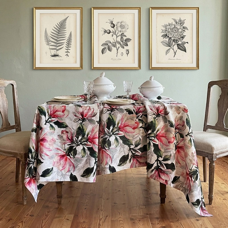 tovaglia-magnolia-rosa7-la-bottega-di-casa Tovaglia in lino stampata Magnolia Allover su tavolo apparecchiato in interno con pareti verde salvia, zuppiere bianche, cristalli e stampe botaniche alle pareti