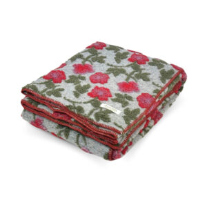 Plaid in lana cotta Amy Grigio piegato, con fiori rossi e foglie verde oliva in rilievo su fondo grigio chiaro e bordo cucito in rosso.