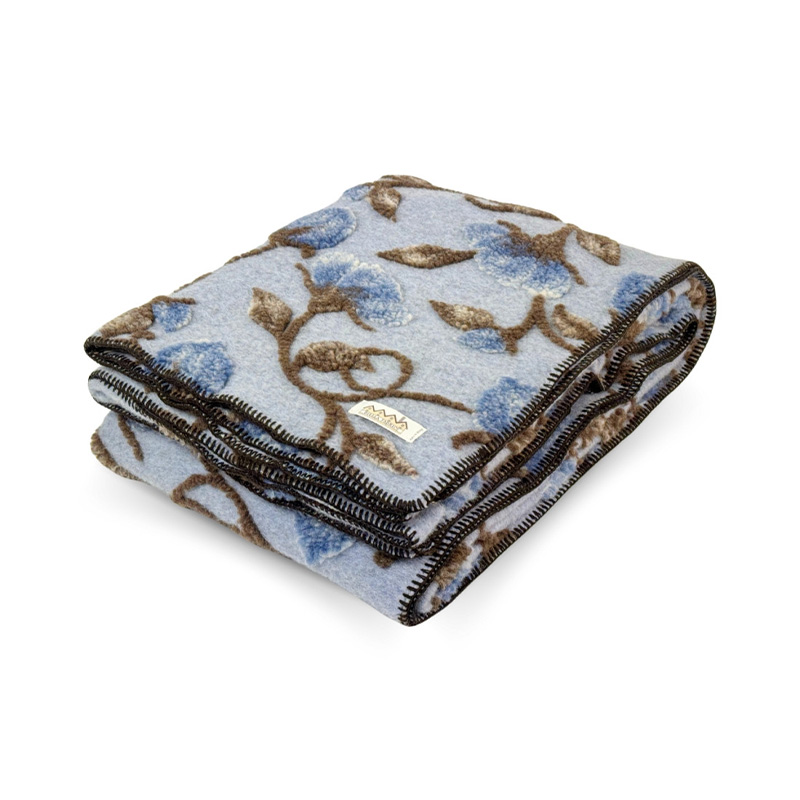 plaid-lana-cotta-Narciso-blu-La-Bottega-di-Casa Plaid in lana cotta Narciso Blu piegato, con fiori blu e tralci marroni in rilievo su fondo azzurro polvere, rifinito con cucitura scura.